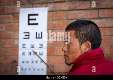 Un moine du monastère d'Amitabha à remplir un test de vision de charité pour les pauvres villageois. Monastère d'Amitabha, Népal Banque D'Images