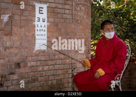 Un moine de l'Amitabha monastère à remplir un test de vision de charité pour les pauvres villageois. Monastère d'Amitabha, Népal Banque D'Images