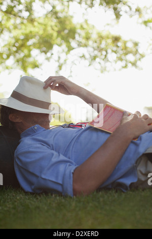 Homme sieste dans l'herbe avec réserve et hat covering face Banque D'Images