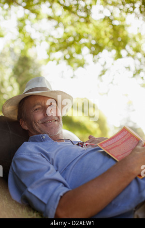 Portrait of smiling man laying in grass with book Banque D'Images