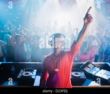 Portrait de DJ enthousiastes avec bras levé et les gens sur une piste de danse en arrière-plan Banque D'Images