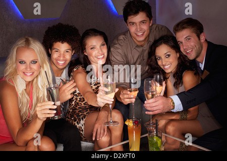 Portrait of smiling friends toasting cocktails in nightclub Banque D'Images