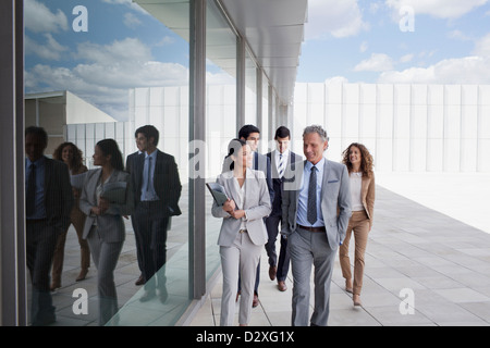 Smiling business people walking along building Banque D'Images