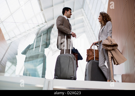 Smiling businessman and businesswoman avec des valises à parler in airport Banque D'Images