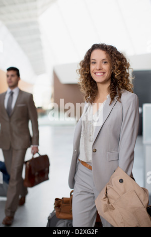 Portrait of smiling businesswoman with suitcase at airport Banque D'Images