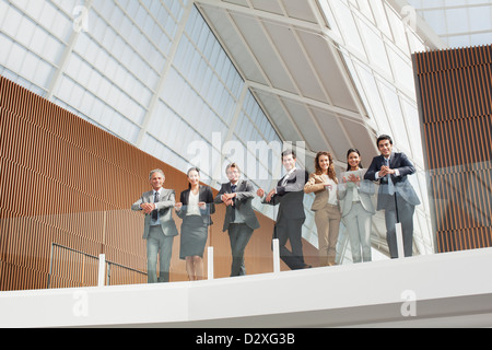 Portrait of smiling business people leaning on railing balcon Banque D'Images