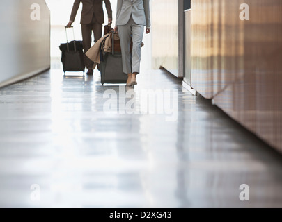 Businessman and businesswoman pulling suitcase in airport ramp down Banque D'Images