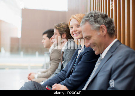 Portrait of smiling businesswoman sitting avec des hommes d'affaires