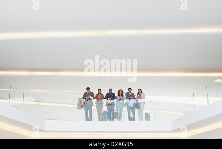 Portrait of business people standing at railing in balcon en verre moderne bureau Banque D'Images