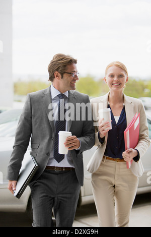 Smiling businessman and businesswoman walking avec tasses à café Banque D'Images