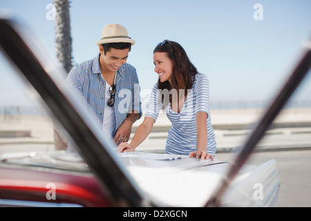 Smiling couple reading road map sur emprunts Banque D'Images