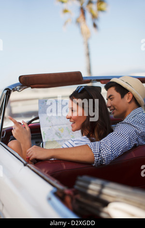 Smiling couple reading road map convertible Banque D'Images