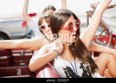 Women cheering in convertible Banque D'Images