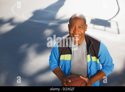 Vieil homme jouant au basket-ball sur cour Banque D'Images