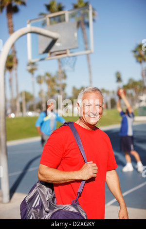 Homme plus âgé exerçant son sac de sport sur cour Banque D'Images