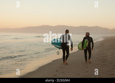 Plus surfers carrying boards on beach Banque D'Images