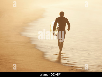 Plus surfer carrying board on beach Banque D'Images