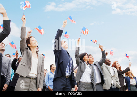 Smiling business people dans la foule agitant des drapeaux américains Banque D'Images