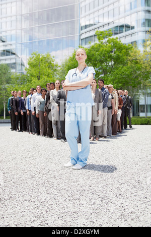 Portrait of confident nurse avec des gens d'affaires en arrière-plan Banque D'Images