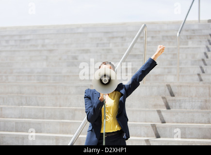 Businesswoman using megaphone sur mesures urbaines Banque D'Images