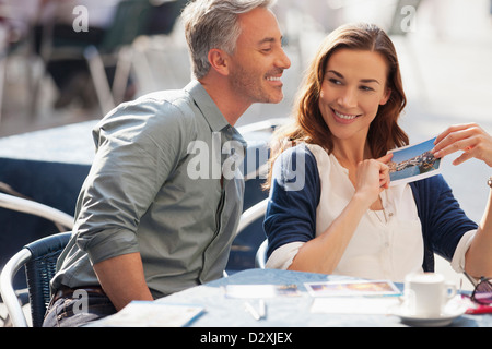 Smiling couple avec postcard at sidewalk cafe Banque D'Images