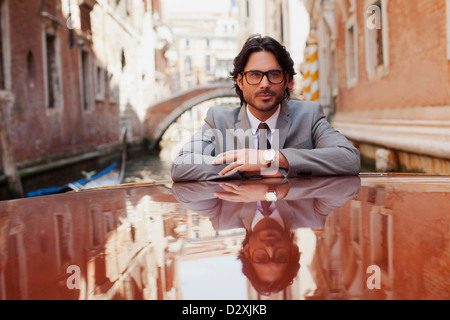 Portrait of serious businessman riding boat in canal à Venise Banque D'Images