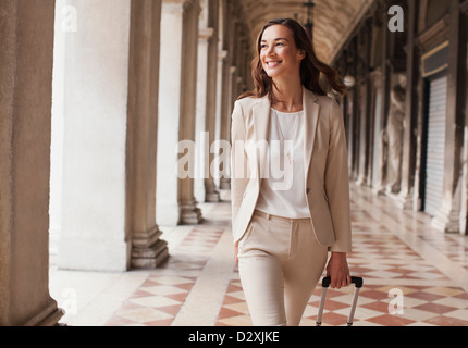 Confiant dans le couloir businesswoman pulling suitcase Banque D'Images