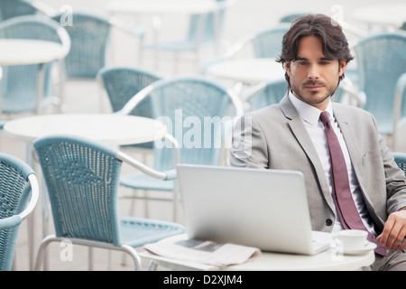 Businessman using laptop at sidewalk cafe Banque D'Images