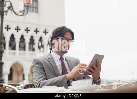 Businessman using digital tablet at sidewalk cafe à Venise Banque D'Images