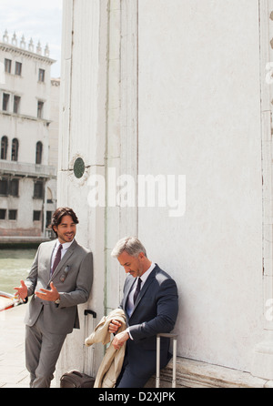 Les hommes d'affaires avec des valises à parler et appuyé contre la construction à Venise Banque D'Images