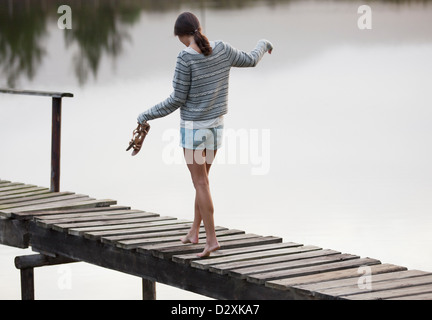 Woman walking along dock sur le lac Banque D'Images