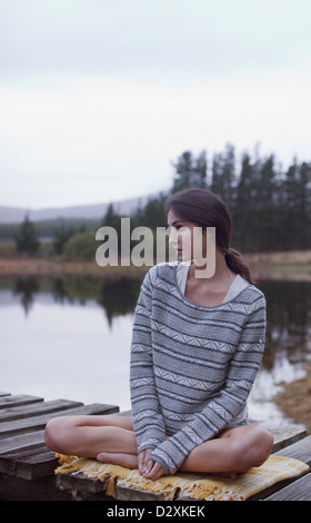 Pensive woman sitting on dock at Lake Banque D'Images