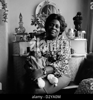 Portrait d'une belle et fière mère noire afro-caribéenne britannique (famille Roper) tenant son petit bébé dans son salon à Leeds West Yorkshire Angleterre Royaume-Uni Grande-Bretagne 1970s 1974 KATHY DEWITT Banque D'Images