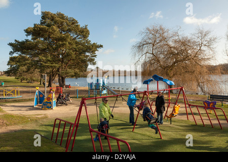 Les parents et les enfants à l'aide d'humeur dans une aire de jeu à Petersfield Lake Banque D'Images