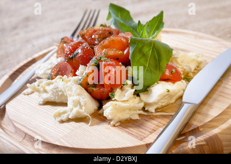 Salade Caprese sur une table ronde en bois avec couteau et fourchette de Peel Banque D'Images