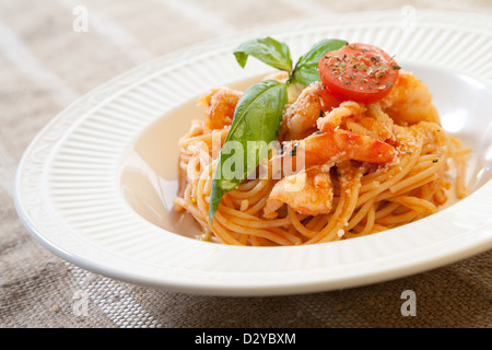 Pâtes aux crevettes et sauce tomate au basilic décoré de tomates cerises et de feuilles Banque D'Images