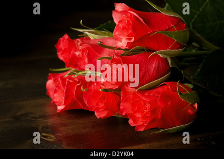 Roses rouges sur un plancher en bois sombre. Banque D'Images