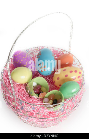 Oeufs de Pâques décorés dans le panier de Pâques avec jelly beans et décoratif rose l'herbe. Isolé sur fond blanc. Banque D'Images