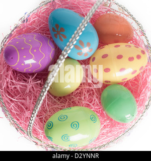 Oeufs de Pâques décorés dans le panier de Pâques avec de l'herbe décorative rose. Isolé sur fond blanc. Banque D'Images