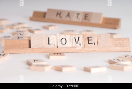 Scrabble en bois letters spelling out 'Love' et 'La haine'. "La haine" en arrière-plan de netteté. Isolé sur fond blanc. Banque D'Images