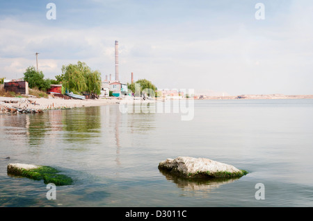 L'activité métallurgique avec de la fumée avec les maisons d'habitation et de la mer sur le devant. Mariupol, Ukraine Banque D'Images