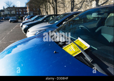 Un billet de stationnement sur le pare-brise d'un véhicule dans un parking. Banque D'Images