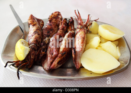 Une plaque de Calmar grillé est servi avec des pommes de terre bouillies à Peniche, Portugal. Banque D'Images