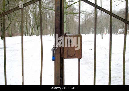 Libre d'une chaîne et de serrure fermée en acier rouillé rétro portes du parc en hiver. Banque D'Images