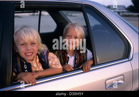 Deux jeunes enfants blond assis à l'arrière d'une voiture à côté de la fenêtre. Banque D'Images