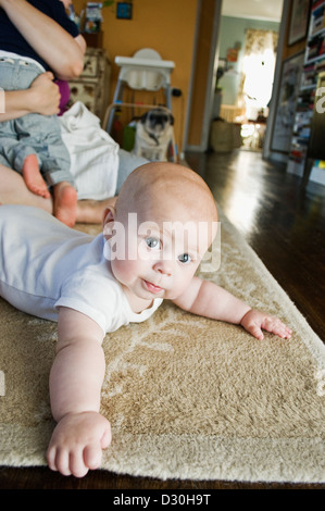 Un bébé de six mois portant sur un tapis dans un appartement de la ville de New York. Banque D'Images