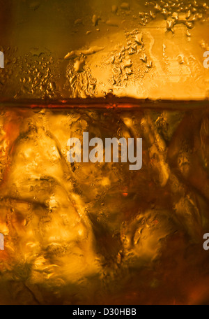 Un gros plan d'un verre de couleur ambre remplis de liquide et de la glace Banque D'Images