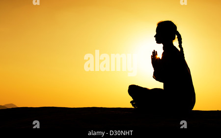 Indian woman praying au coucher du soleil dans la campagne indienne. Silhouette. L'Inde Banque D'Images