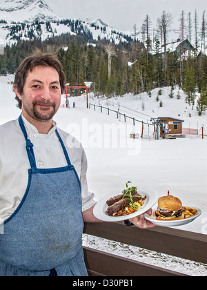 Chef Frederik Bergkvist de Corner Pocket Brasserie à Fernie détient ses deux plats, un burger de bison braisé et côtes courtes. Banque D'Images