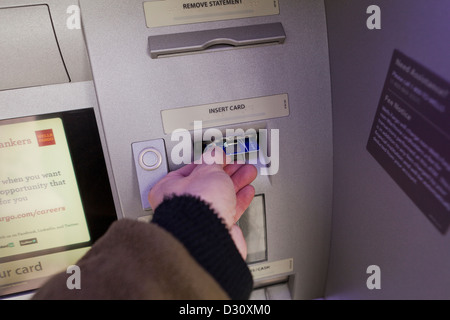 L'homme l'insertion de carte dans un guichet automatique bancaire Banque D'Images